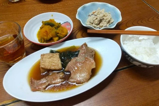 豚肉と厚揚げの煮物、カボチャの煮付け、おから、ご飯、飲み物が並んだ和食の定食。