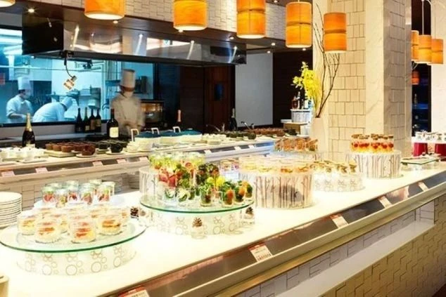 ホテルや旅館のバイキングレストラン。豪華な料理が並ぶビュッフェカウンターと調理補助の仕事風景。