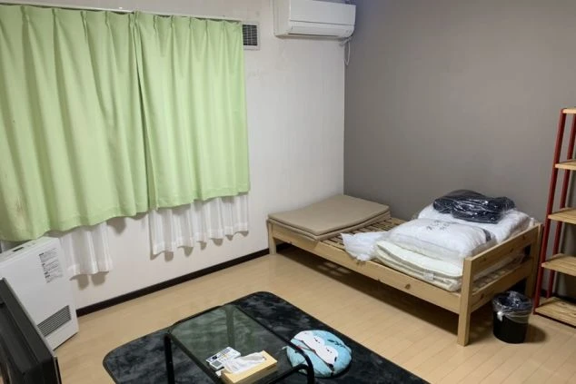 フローリングの洋室にベッド、テレビ、エアコン、暖房器具が完備された、リゾートバイトスタッフ用の個室寮の画像。