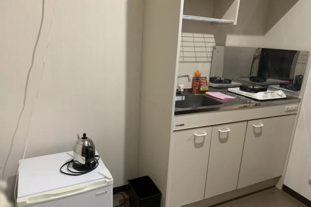 寮内に完備されたミニキッチンの画像。IHコンロ、シンク、小型冷蔵庫、電気ケトル完備。