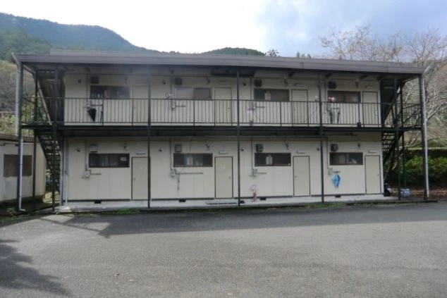 山々に囲まれたリゾートバイト寮の外観画像。2階建てのアパートタイプで、各部屋にバルコニーがあり、プライベートが確保された寮生活を送れる。