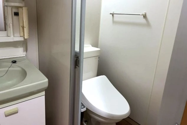 客室寮に備え付けの洗面台とトイレの画像。温水洗浄便座付きで、清潔感のある専用の水回り設備。