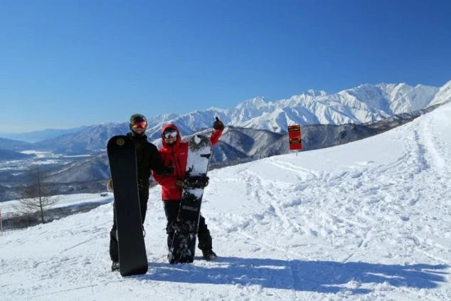 長野 白馬のゲレンデ上部でスノーボードを持つ二人。