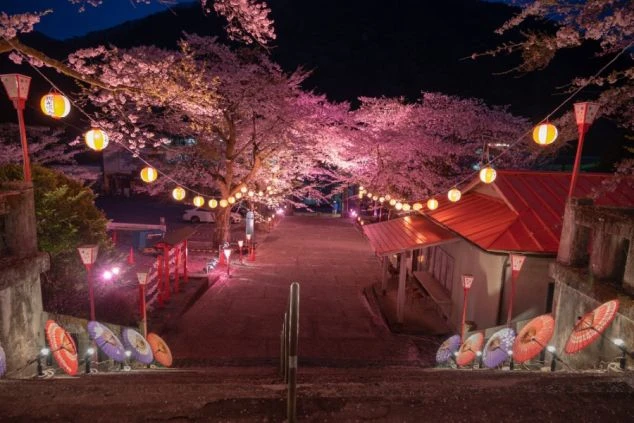 鬼怒川温泉街の秋の風景画像。紅葉した山と川沿いに並ぶ温泉旅館やホテルが見える。