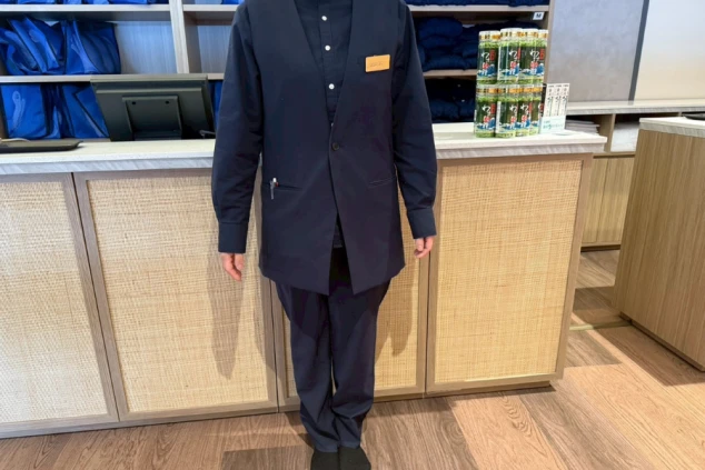 紺色のジャケットを着用したフロントスタッフの全身写真。