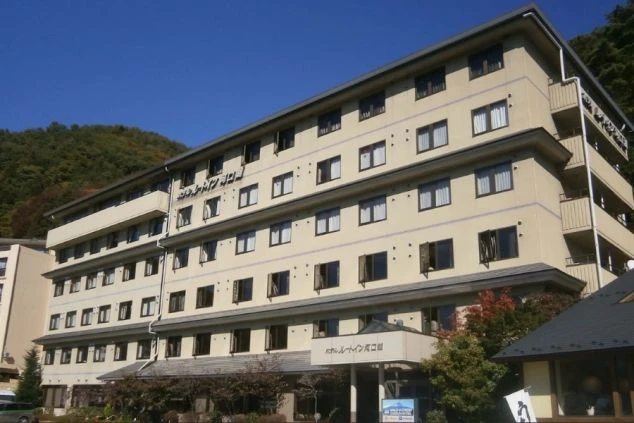 山々に囲まれた立地にある、落ち着いた色合いのホテル外観。