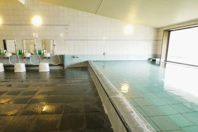 清潔感のあるタイル張りの大浴場。大きな窓の外の景色を楽しめる温泉。