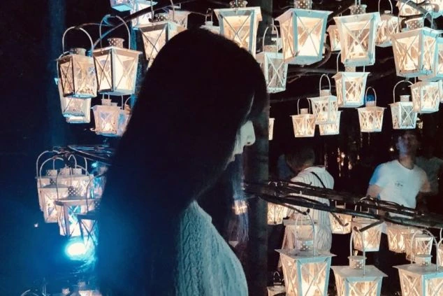 幻想的なランタンの光に囲まれ、横顔を見せる女性。リゾートバイト中の特別な夜。