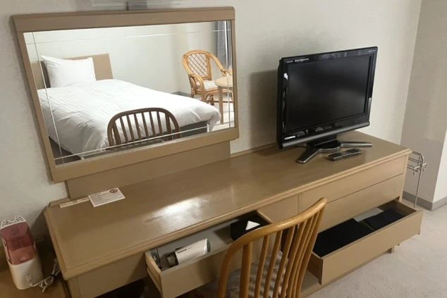 リゾートバイトの寮に完備されているテレビとデスクの画像。客室寮で、ドライヤーなどの備品も揃っている快適な環境。