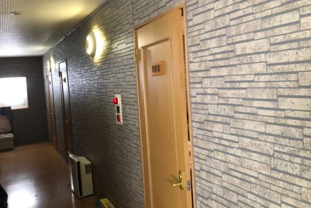 リゾートバイト寮の館内廊下。レンガ調の壁紙がおしゃれな落ち着いた雰囲気で、プライバシーも守られた環境。