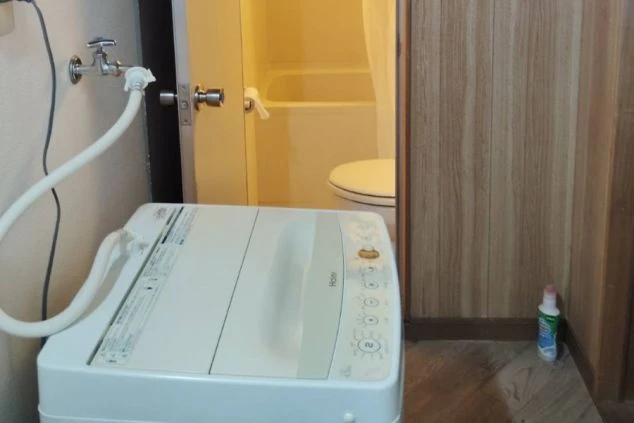 寮内に設置された個人用洗濯機とバスルームの写真。