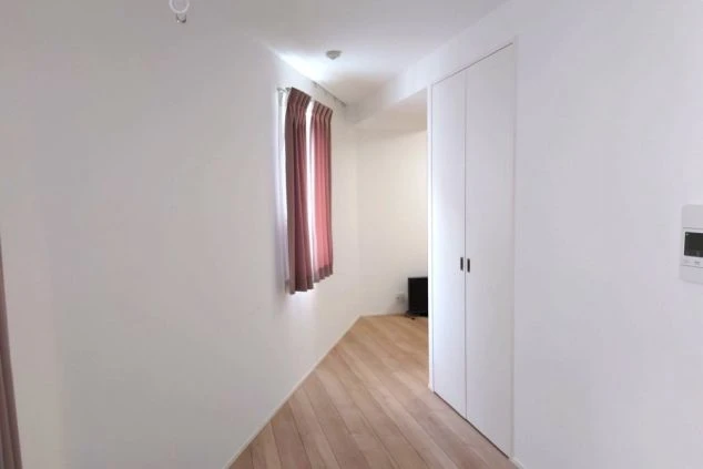 女性寮の個室。木目調のフローリングと白い壁で、クローゼット付きの明るい部屋。