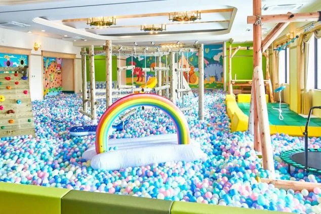 虹のオブジェがあるカラフルなボールプール。子供と楽しく働けるリゾート施設の仕事です。