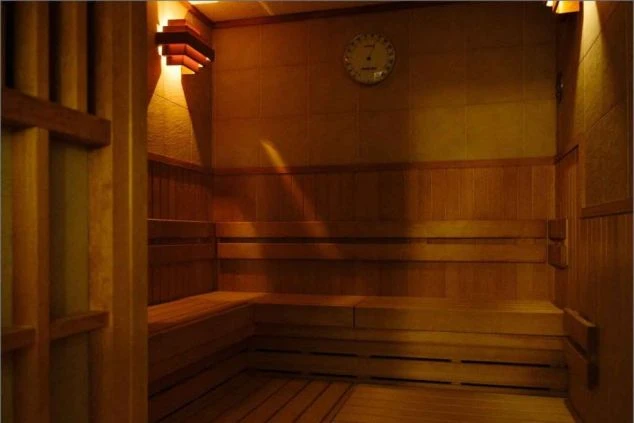 木製のベンチが並び、温かい光が灯るサウナルームが映るイメージ画像。無料で利用可能。