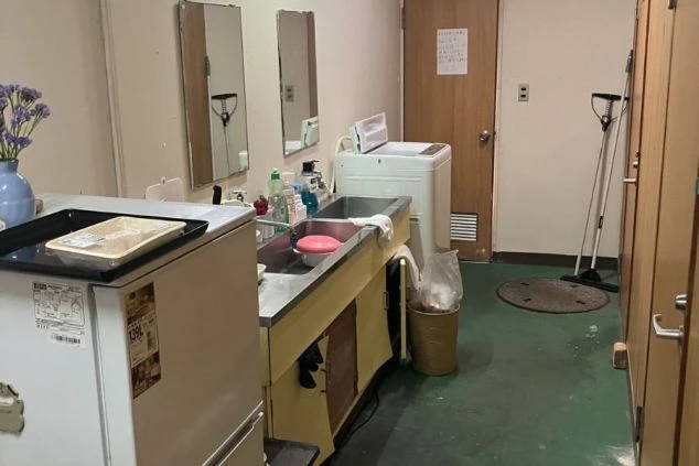 リゾートバイト寮の共用キッチンと洗濯機。自炊に便利なシンクや調理スペースがあり、生活必需品も揃っています。住み込みのリゾートバイトで充実した生活を送るための寮設備。