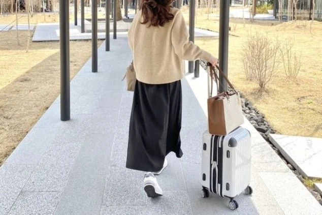 キャリーケースを引いてリゾートバイトの寮へ向かう女性の画像。