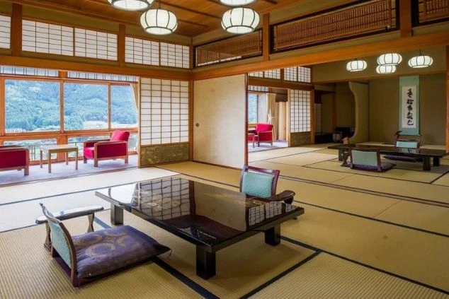 眺望の良い窓から山々が見える旅館の広々とした和室の画像。畳に座卓と座椅子が置かれた客室。リゾートバイトで働く温泉旅館の部屋。
