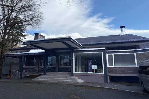 栃木県奥日光にあるホテルの屋根付きのエントランスがある落ち着いた外観の画像。