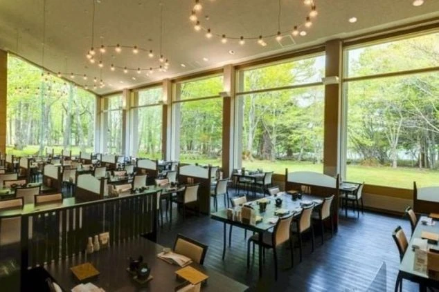 茶色のテーブルと椅子が並んだ、照明が特徴的な広々としたレストランの画像。