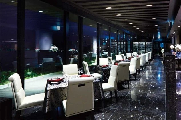 窓の外に夜景が広がる、モダンで高級感のあるレストランのダイニングエリア。