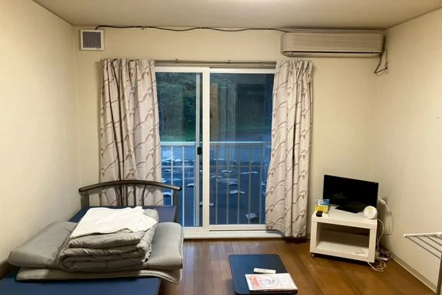 リゾートバイトの完全個室寮の室内。ベッド、テレビ、エアコンなどの家具家電が完備された、すぐに暮らせる洋室。