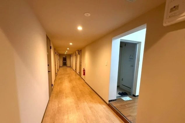 リゾートバイト寮の館内廊下。清掃が行き届いた清潔な通路で、各個室への動線もスムーズな居住環境。