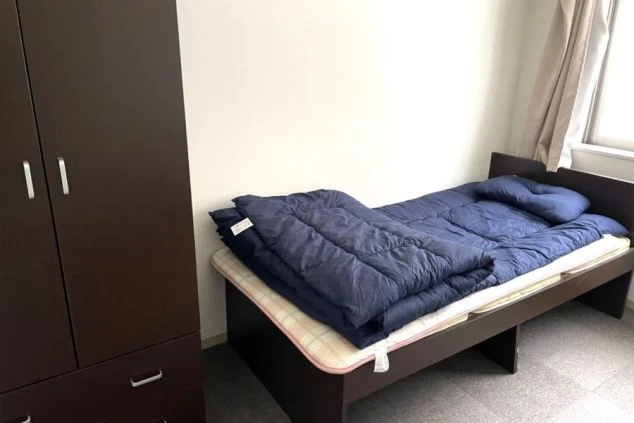 リゾートバイトの男性寮の部屋の画像。ベッドの足元にクローゼットがある。