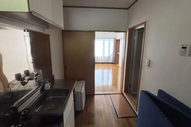 リゾートバイトの個室寮のキッチンの画像。小型冷蔵庫があり、奥には親切がある。