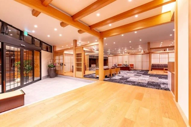 明るい木目調の広々とした和モダンな旅館ロビー。接客やベルスタッフが活躍するリゾートバイトの職場環境。