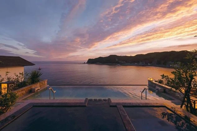 夕暮れの海を望む温泉露天風呂があるリゾート施設の写真