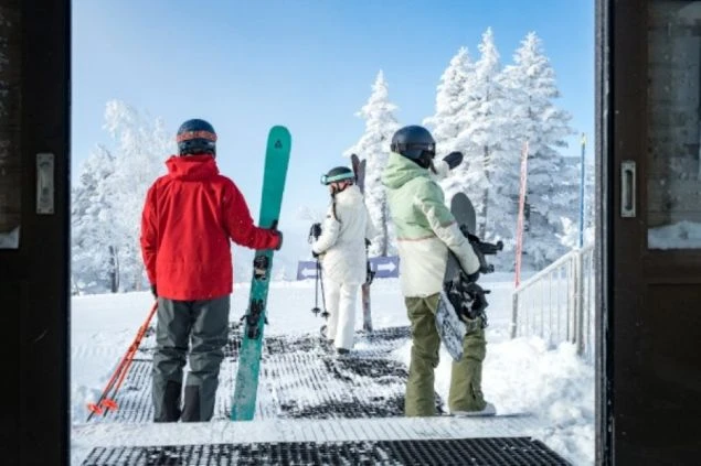 雪景色の中、スキー場から外に出ようとするスキーヤーとスノーボーダーの画像。