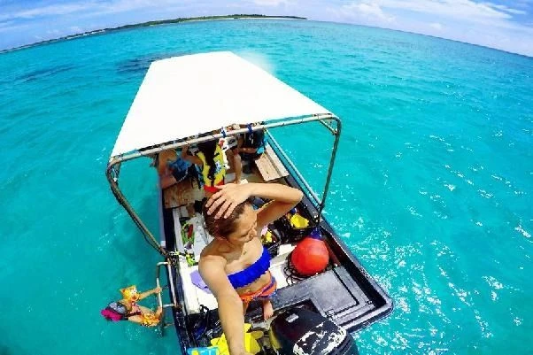 南国リゾートの透き通った海でのマリンスタッフの仕事風景。ボートに乗ってお客様をサポート。