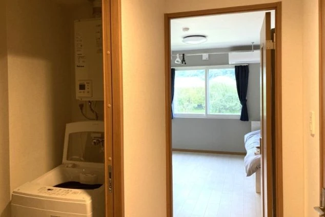 部屋の入り口付近にある収納スペースに、洗濯機と給湯器が設置されている様子。