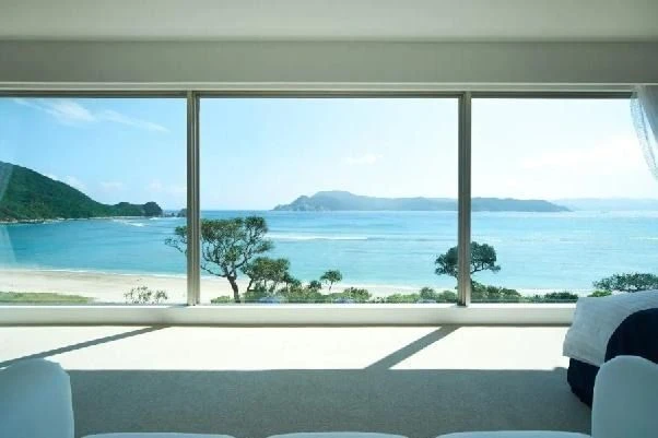 リゾートホテルの客室から望む絶景オーシャンビュー。大きな窓一面に広がる青い海と白い砂浜。