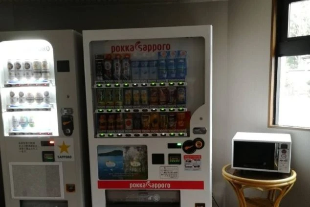 寮内の共用スペースにある自動販売機と電子レンジ。夜食や休憩時に便利な、リゾートバイト生活を支える設備。