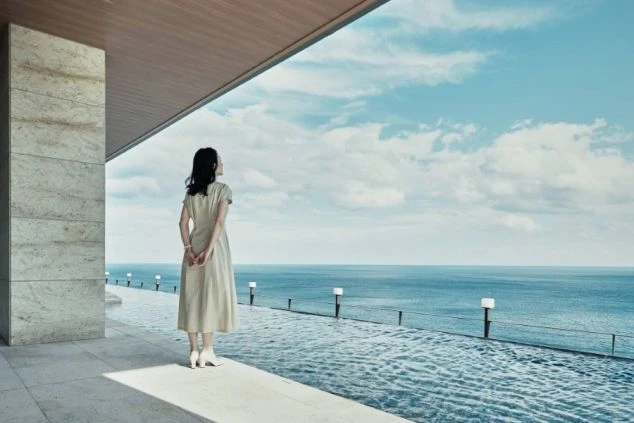 施設からの絶景を臨む女性の写真。美しい海の近くで過ごせるリゾートバイト。