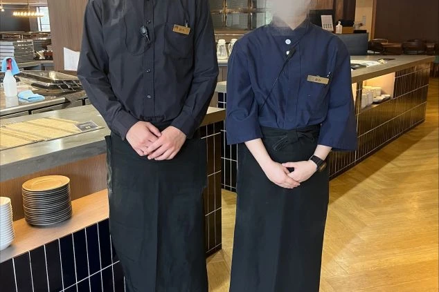 落ち着いたネイビーや黒のシャツにエプロンを合わせたレストランホールの制服。