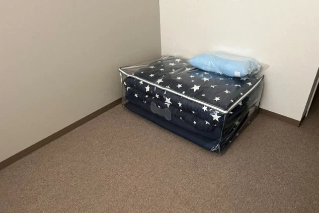 カーペット敷きの部屋の隅に置かれた、星柄の布団セット。透明なケースに収納されています。