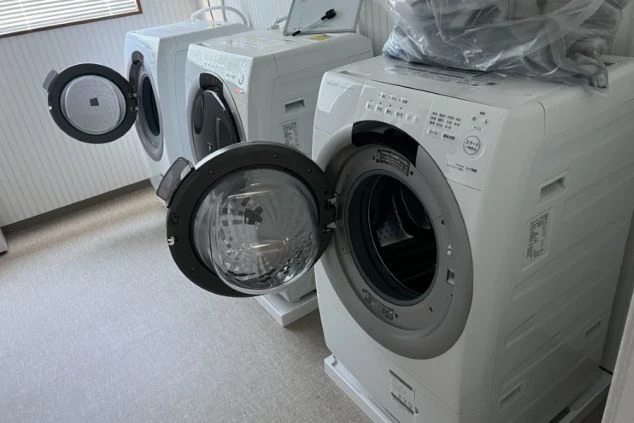 寮の共同ランドリーにあるドラム式洗濯機。リゾートバイト生活に便利な、設備が充実した寮のイメージ。