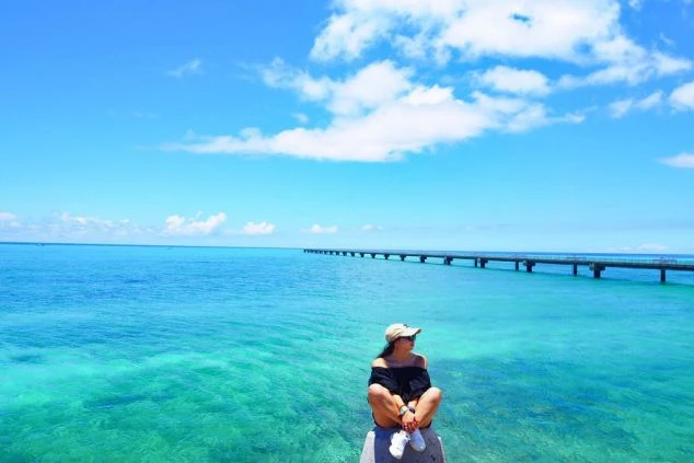 リゾートバイトで訪れる沖縄の美しい海と青空。海辺でくつろぐスタッフのイメージ