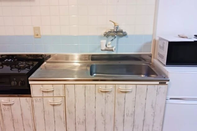 個室内に設置されたシステムキッチンと、すぐ横に用意された全自動洗濯機。自炊や洗濯が室内で完結する、非常に利便性の高いリゾートバイト寮の設備環境。