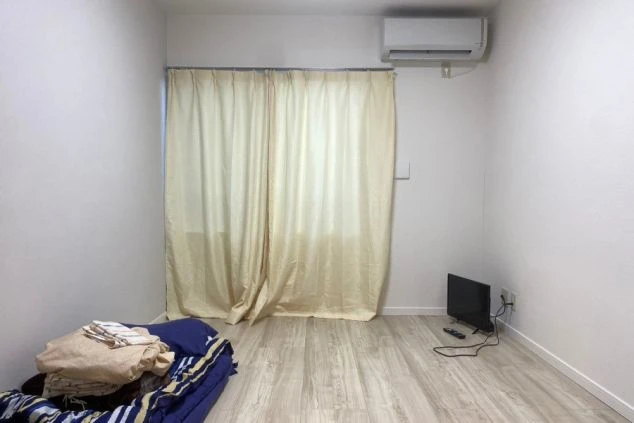 リゾートバイト寮の居室。大きな窓とエアコン、テレビが備え付けられ、フローリングの床が清潔感を保っている。