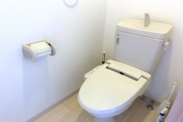 寮の清潔なトイレ。ウォシュレット機能付きの洋式便器とトイレットペーパーホルダー。
