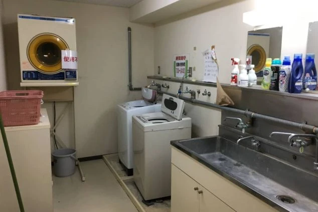 ALTテキスト： リゾートバイト先のスタッフ専用寮にある洗濯機とランドリースペース。生活備品が完備された寮の周辺環境イメージ。