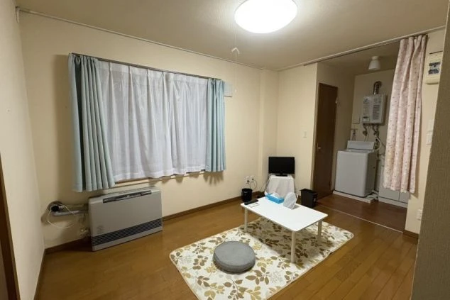 寮の居室。テレビ、テーブル、暖房器具が完備された広々としたフローリングの個室。