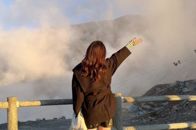 大涌谷のダイナミックな噴煙を背に、箱根の自然を満喫する女性の画像。休日に有名観光地を巡りながらリフレッシュできる、箱根エリアのリゾートバイト生活。