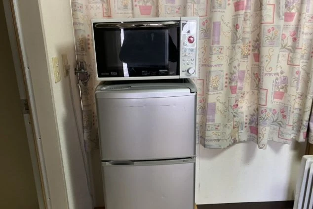 リゾートバイトの個室寮に備え付けられたミニ冷蔵庫と電子レンジ。自炊や簡単な調理ができる便利な設備の画像。
