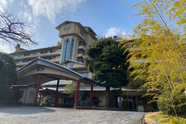 竹林と豊かな緑に包まれた、伝統的な建築様式が美しい温泉旅館の施設外観画像。