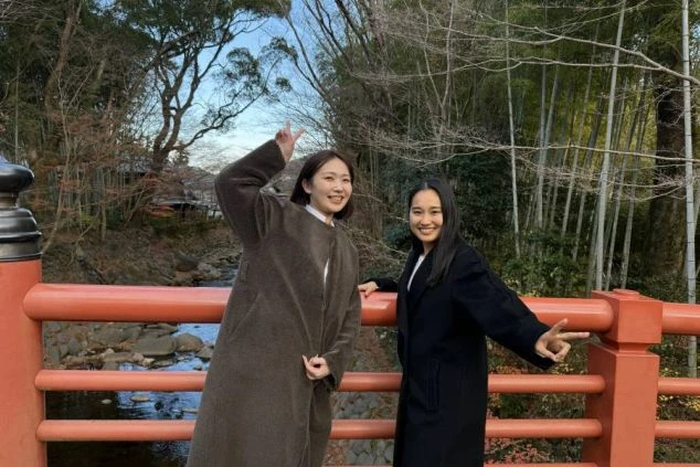 リゾートバイト中の休日を楽しむ女性スタッフ。伊豆・修善寺の赤い橋と竹林を背景にした観光の様子