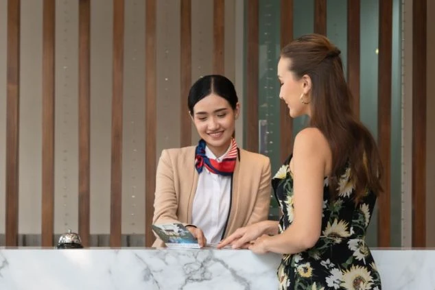 ホテルのフロントで笑顔で接客するスタッフ。